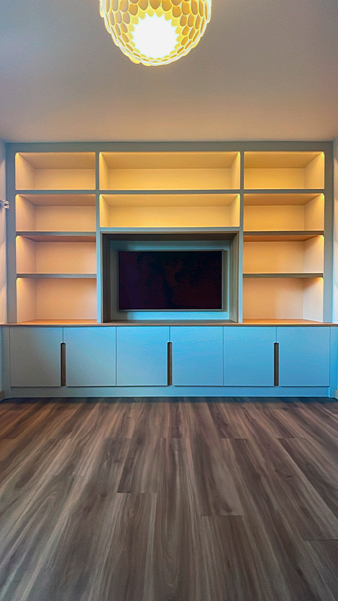 Contemporary fitted media wall with illuminated shelving and oak details