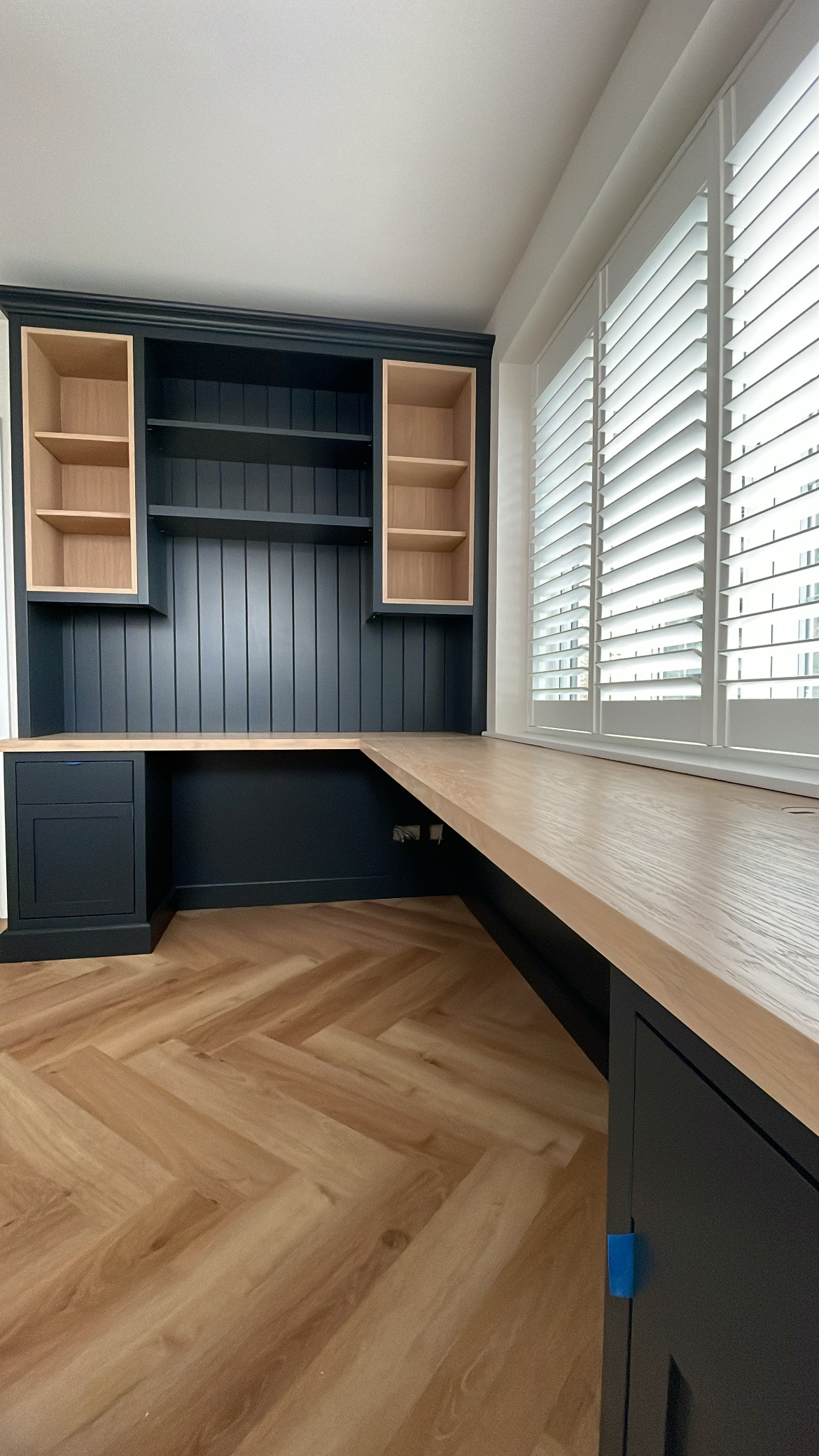 Deep blue fitted home office with oak desk and open shelving