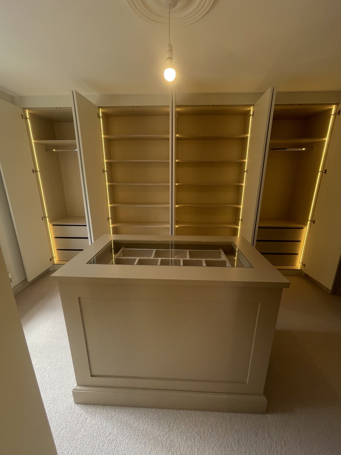 Walk-in dressing room with illuminated fitted wardrobes and central island