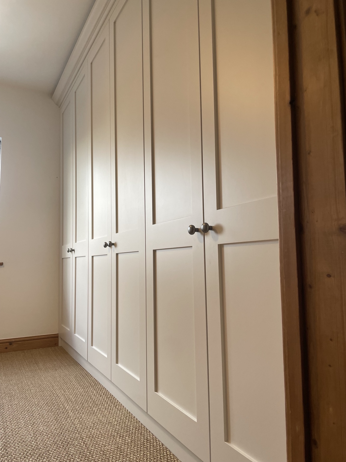 Traditional painted fitted wardrobes arranged around an original timber beam