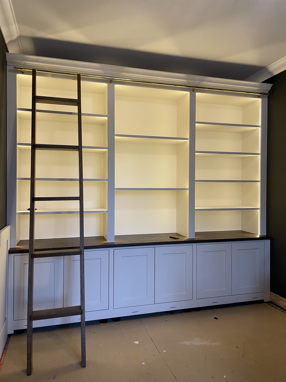 Floor-to-ceiling library bookcase with traditional rolling ladder