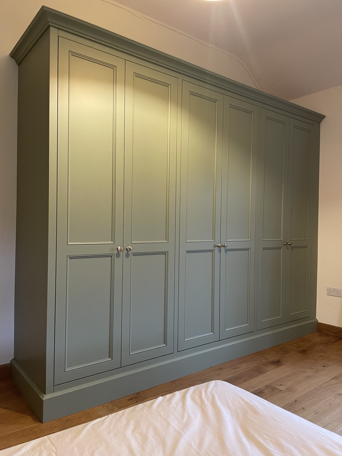 Full run of sage green fitted wardrobes