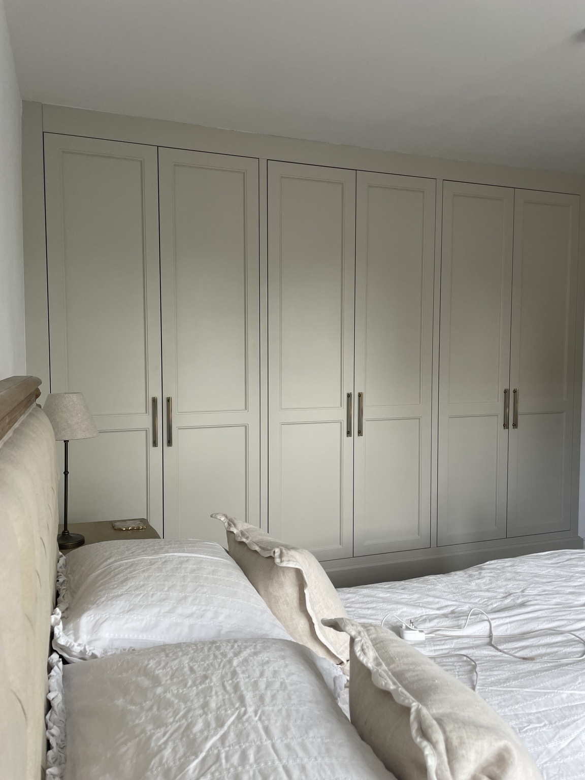 Wall of painted fitted wardrobes with long metal handles
