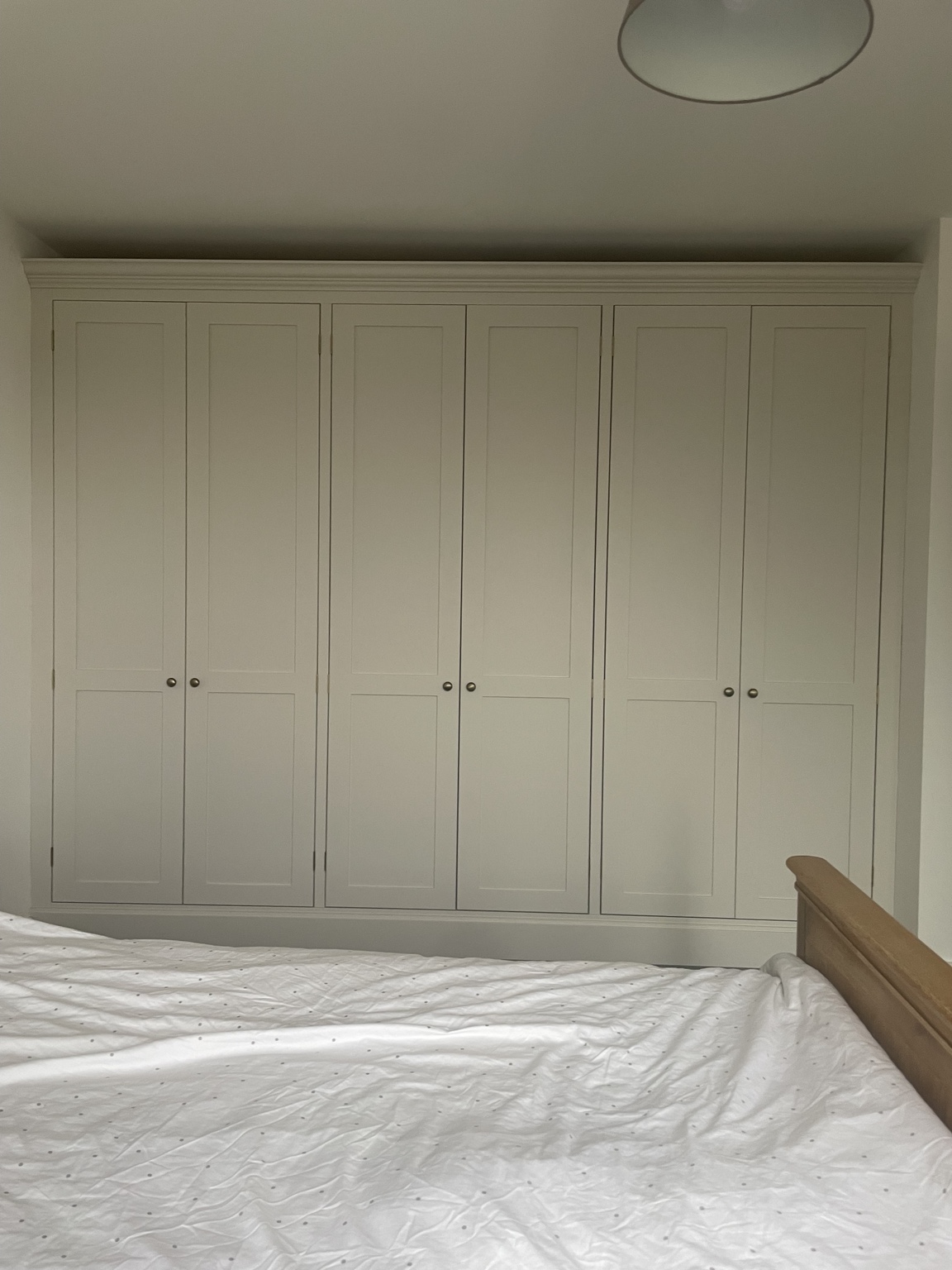 Wall of painted fitted wardrobes with round metal knobs